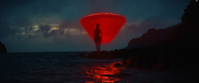 a person standing on a rock in the ocean at night