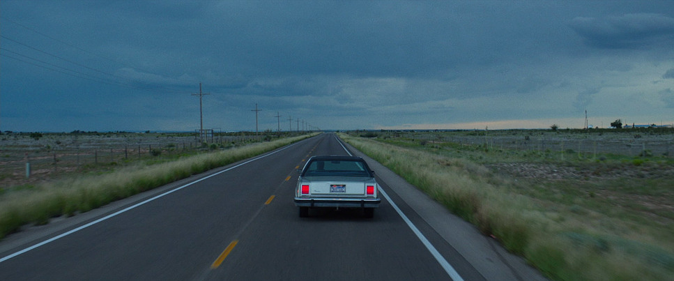 a car driving down a road under a cloudy sky