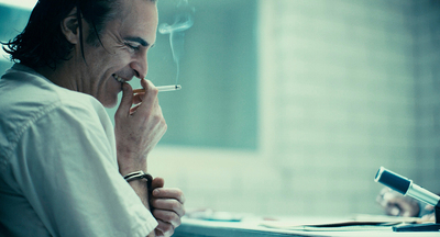 a man sitting at a desk smoking a cigarette