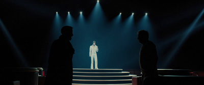 a man in a white suit standing on a stage