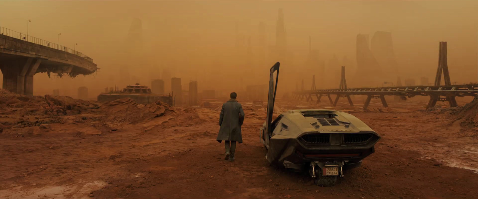 a man standing next to a car on a dirt field