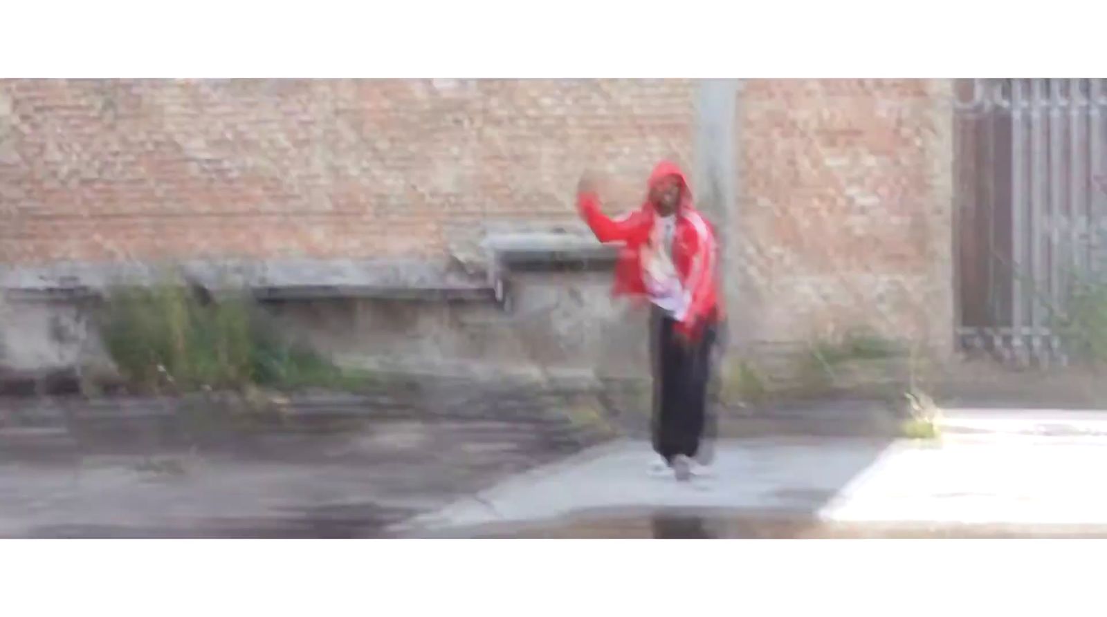 a man in a red jacket is walking on a sidewalk