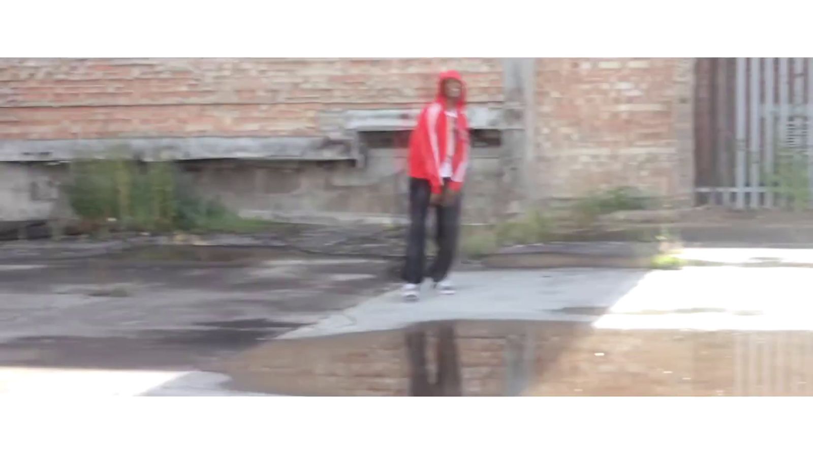 a man in a red hoodie standing on a sidewalk