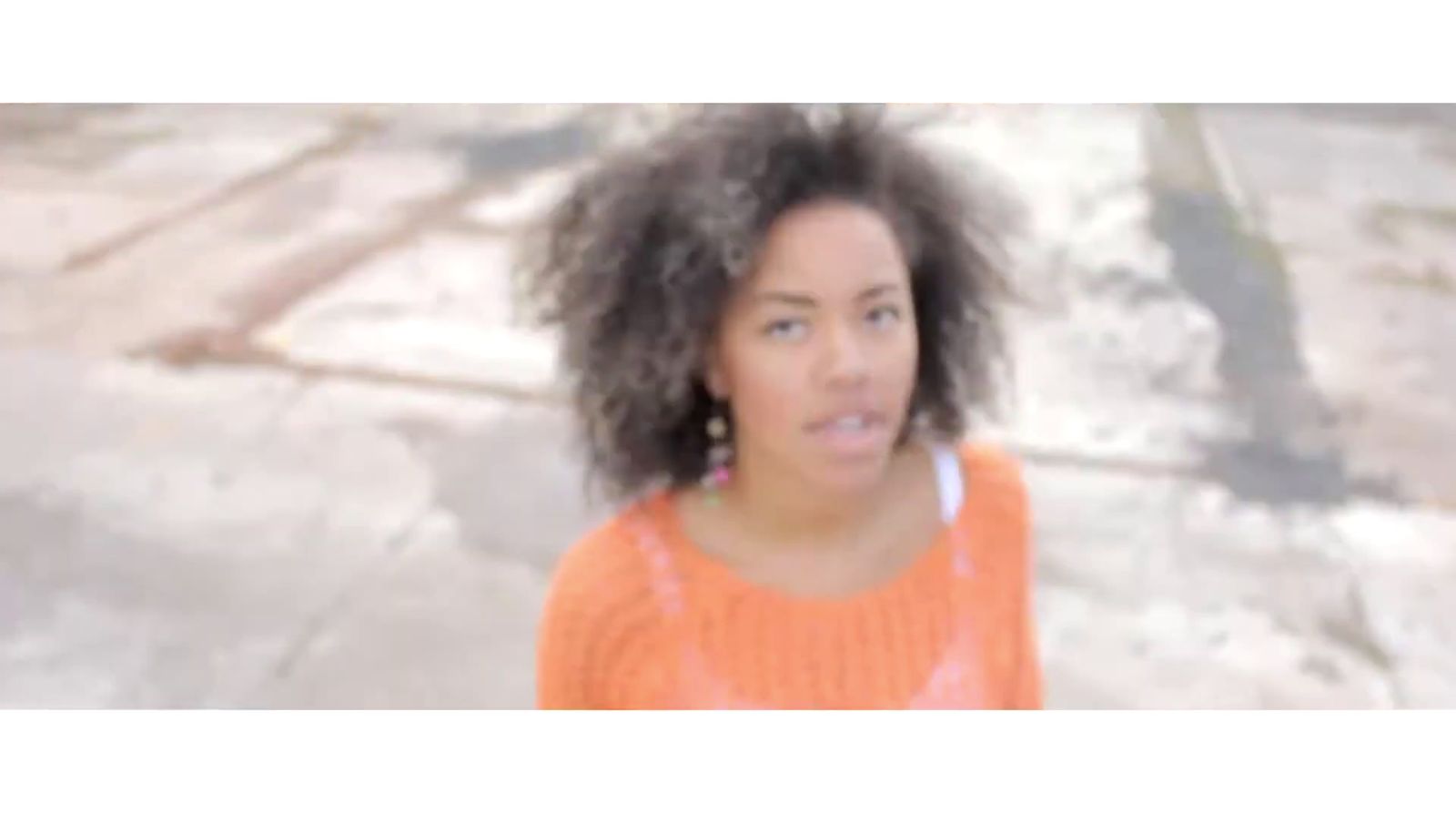 a woman with an orange sweater and earrings