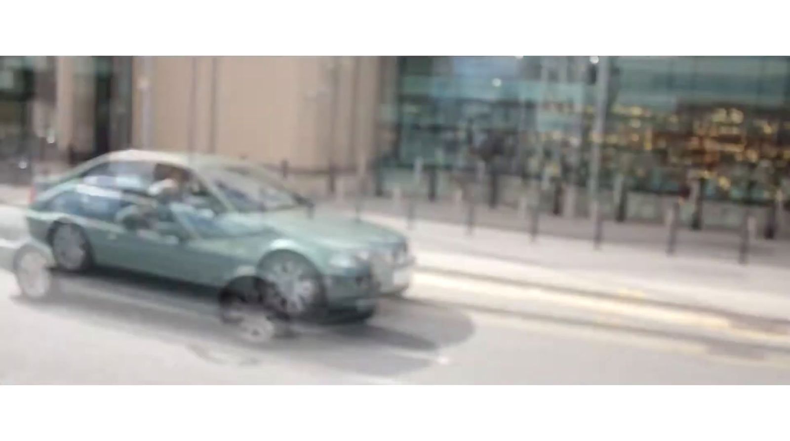 a car driving down a street next to a tall building