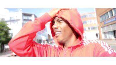 a man in a red hoodie standing on a street