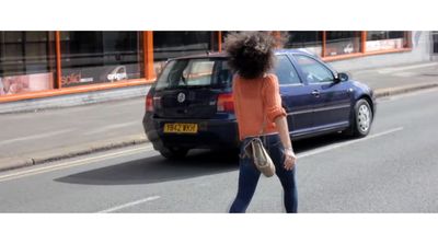 a woman crossing the street in front of a car