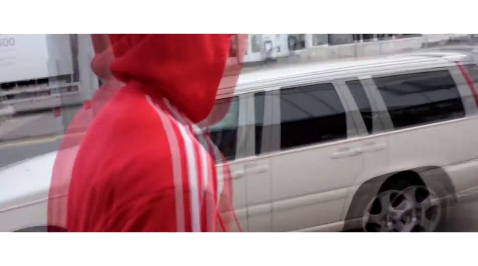 a man in a red hoodie standing next to a white van