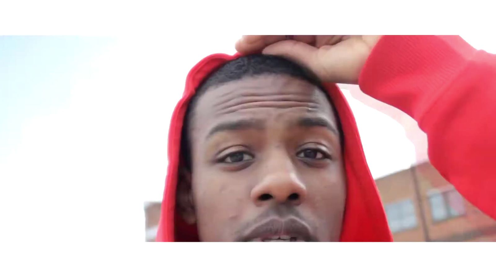 a man in a red hoodie is covering his face