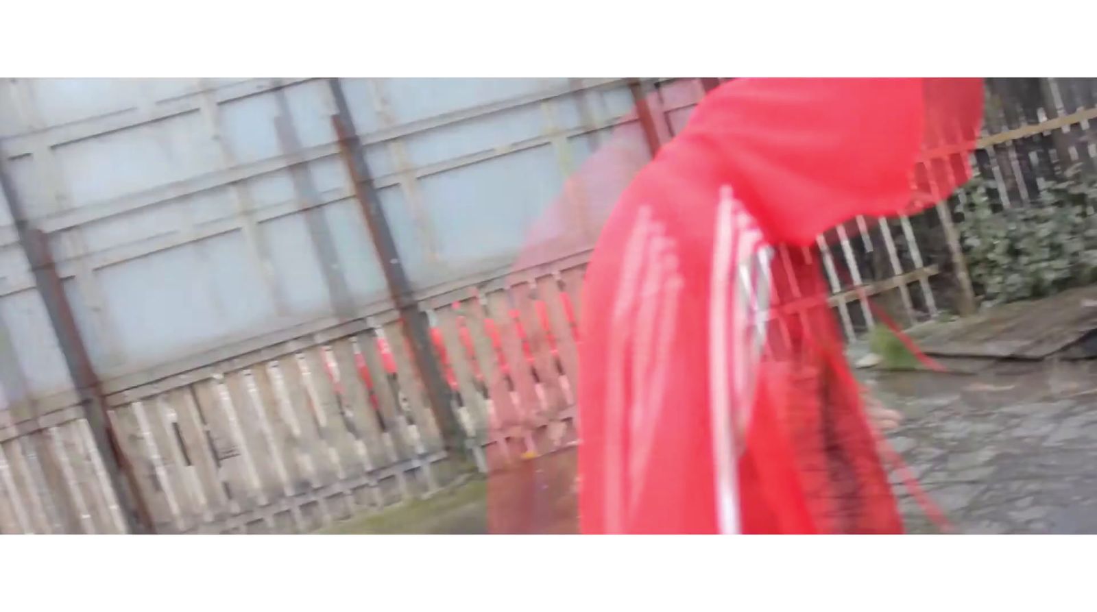 a blurry photo of a red umbrella in front of a fence