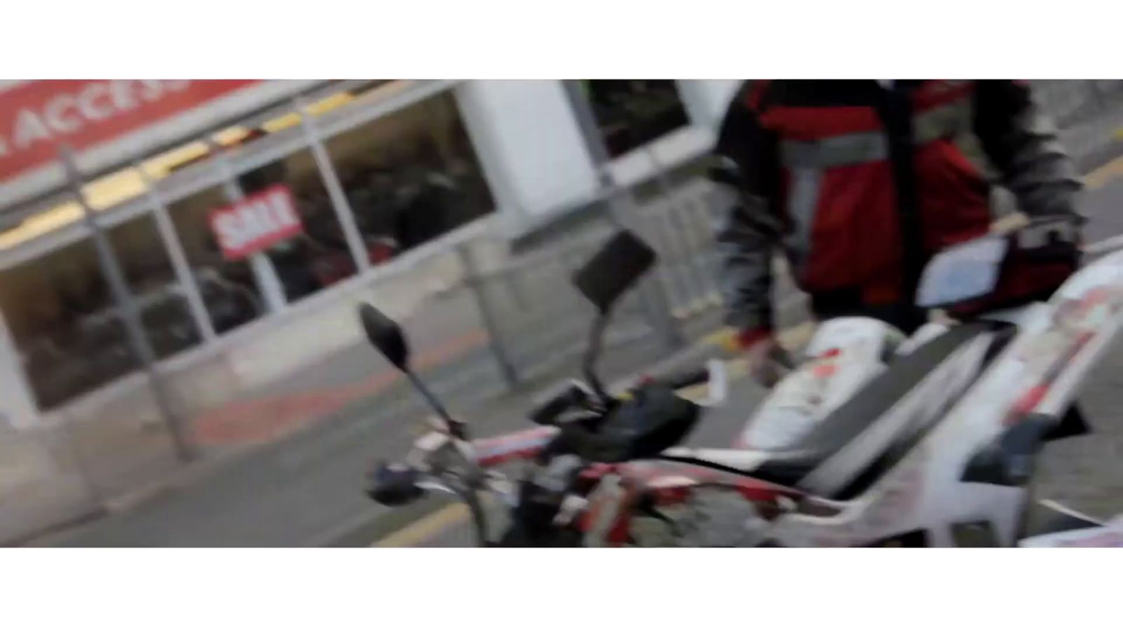 a man walking down a street next to a motorcycle