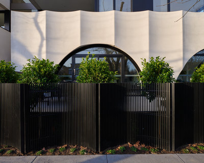 a black metal fence with trees in front of a building