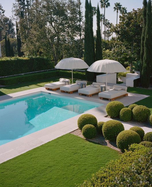 a pool with lawn chairs and umbrellas next to it