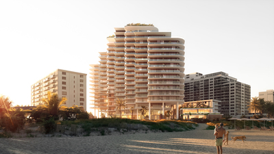 a woman walking on a beach next to a tall building