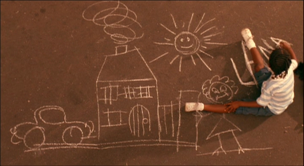 a child drawing a house on the ground with chalk