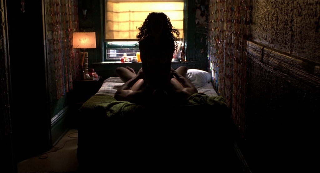 a woman sitting on a bed in a dark room