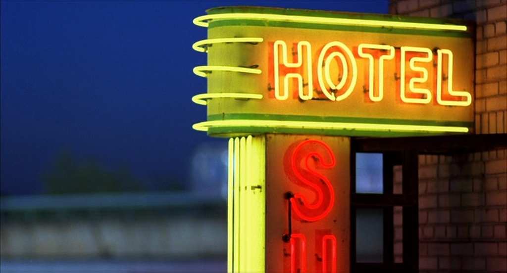 a neon hotel sign lit up at night