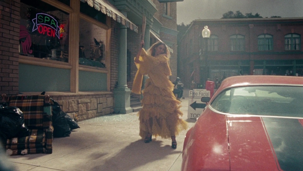 a woman in a yellow dress walking down a street