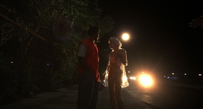 a man and a woman standing on a sidewalk at night