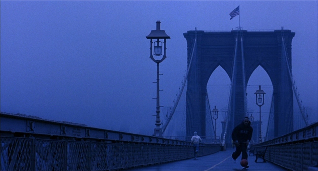 a man walking across a bridge on a foggy day