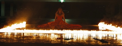 a woman in a red dress is surrounded by fire