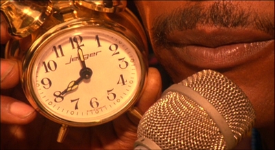 a close up of a person holding a microphone and an alarm clock