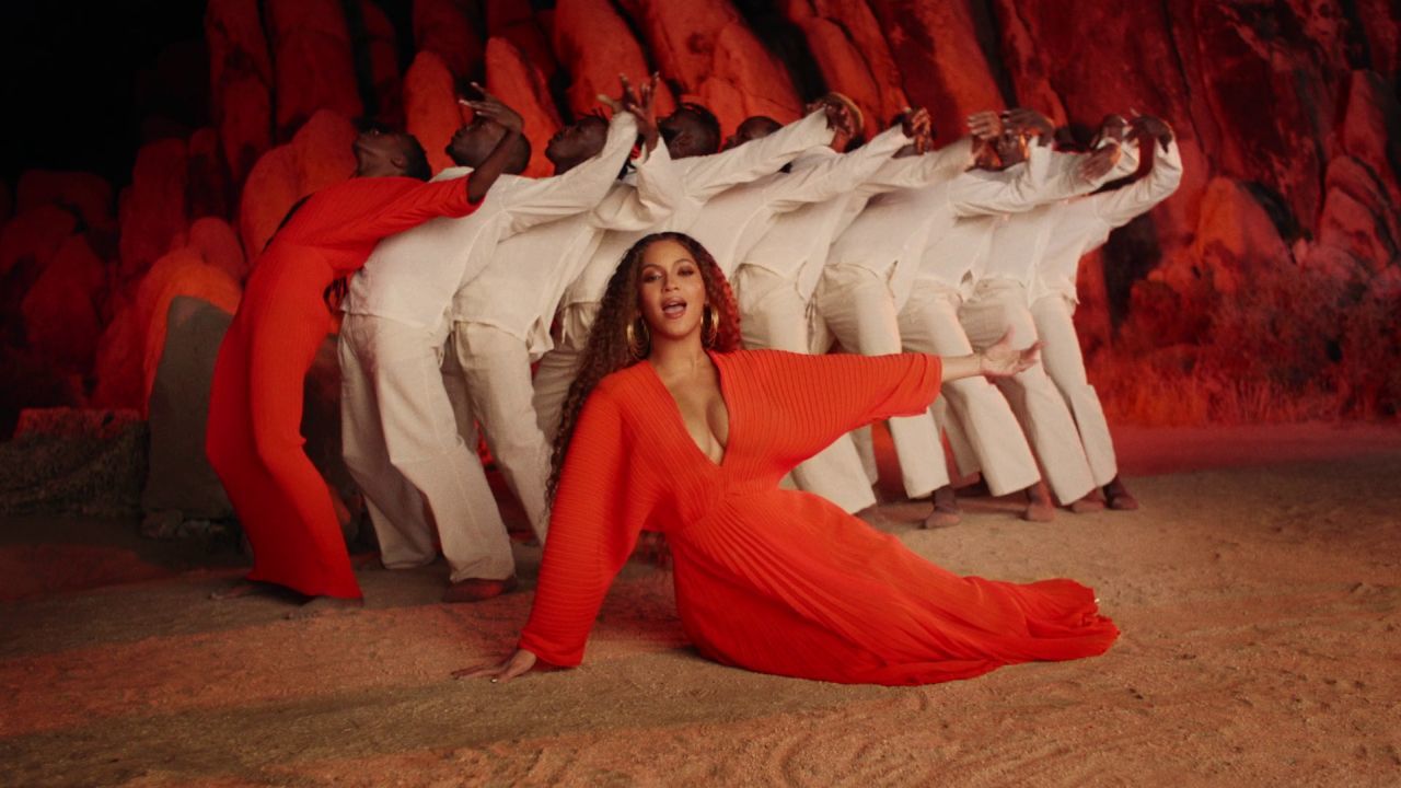 a woman in a red dress sitting in front of a group of white men