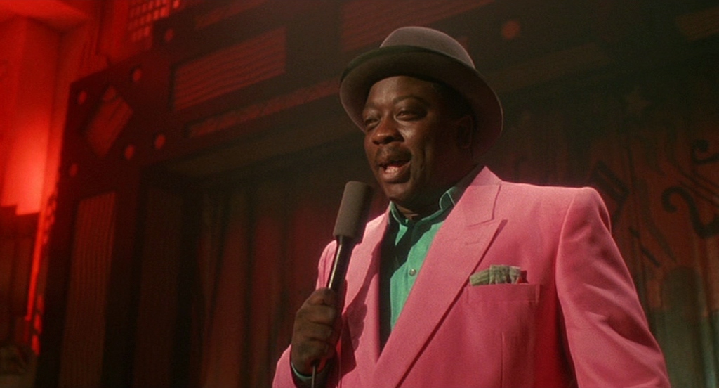 a man in a pink suit holding a microphone