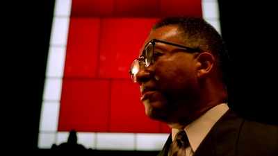 a man in a suit and tie standing in front of a red wall