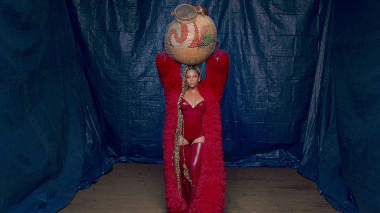 a woman in a red outfit is holding a ball above her head