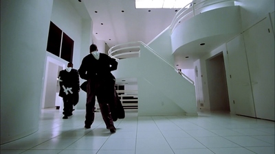 a man walking down a hallway next to a stair case