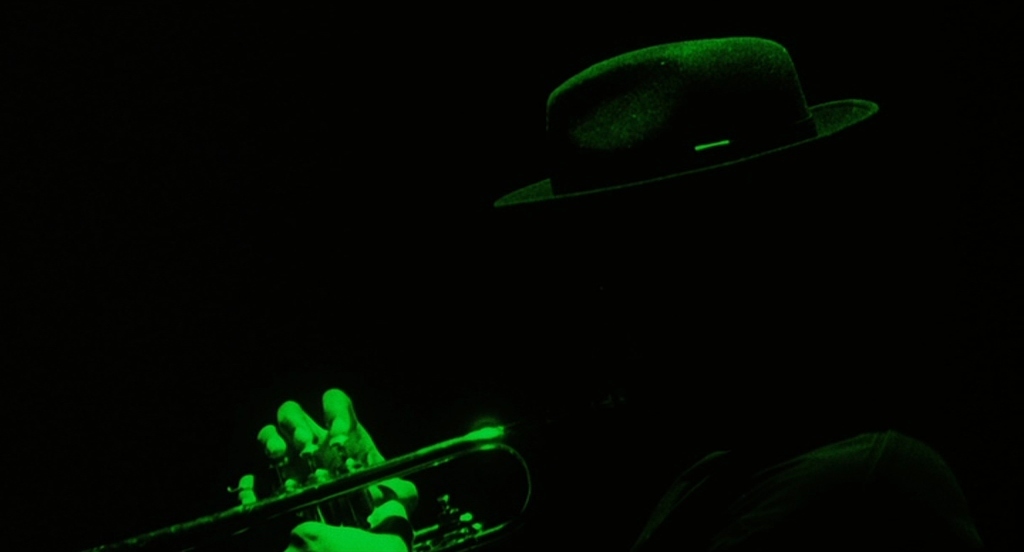 a man with a hat and a trumpet in the dark