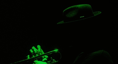 a man with a hat and a trumpet in the dark