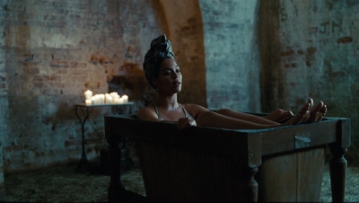 a woman in a bathtub with candles in the background