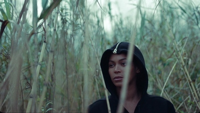 a woman in a black hoodie standing in tall grass