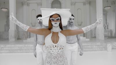 a woman in a white dress with her hands in the air