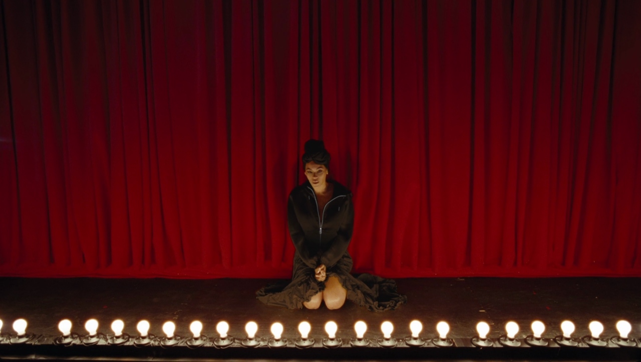 a woman sitting on a stage surrounded by candles