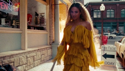 a woman in a yellow dress walking down the street