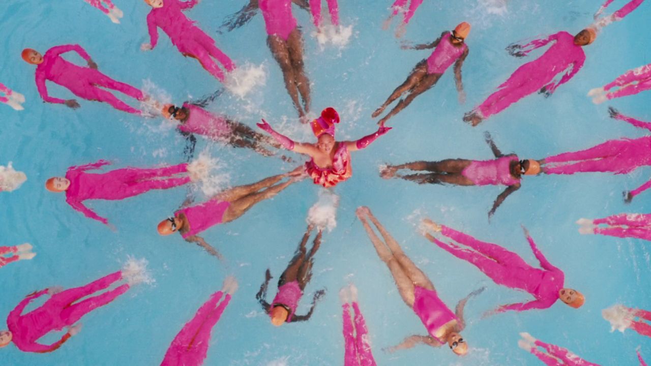 a group of people in pink swimsuits floating in a pool