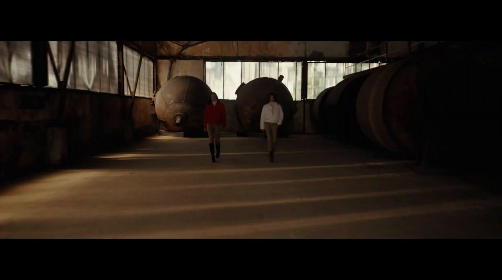 a man walking down a hallway next to barrels