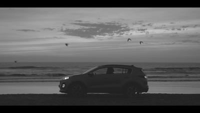 a black and white photo of a car on the beach