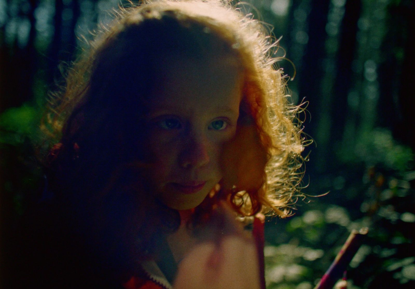 a young girl with long red hair standing in the woods