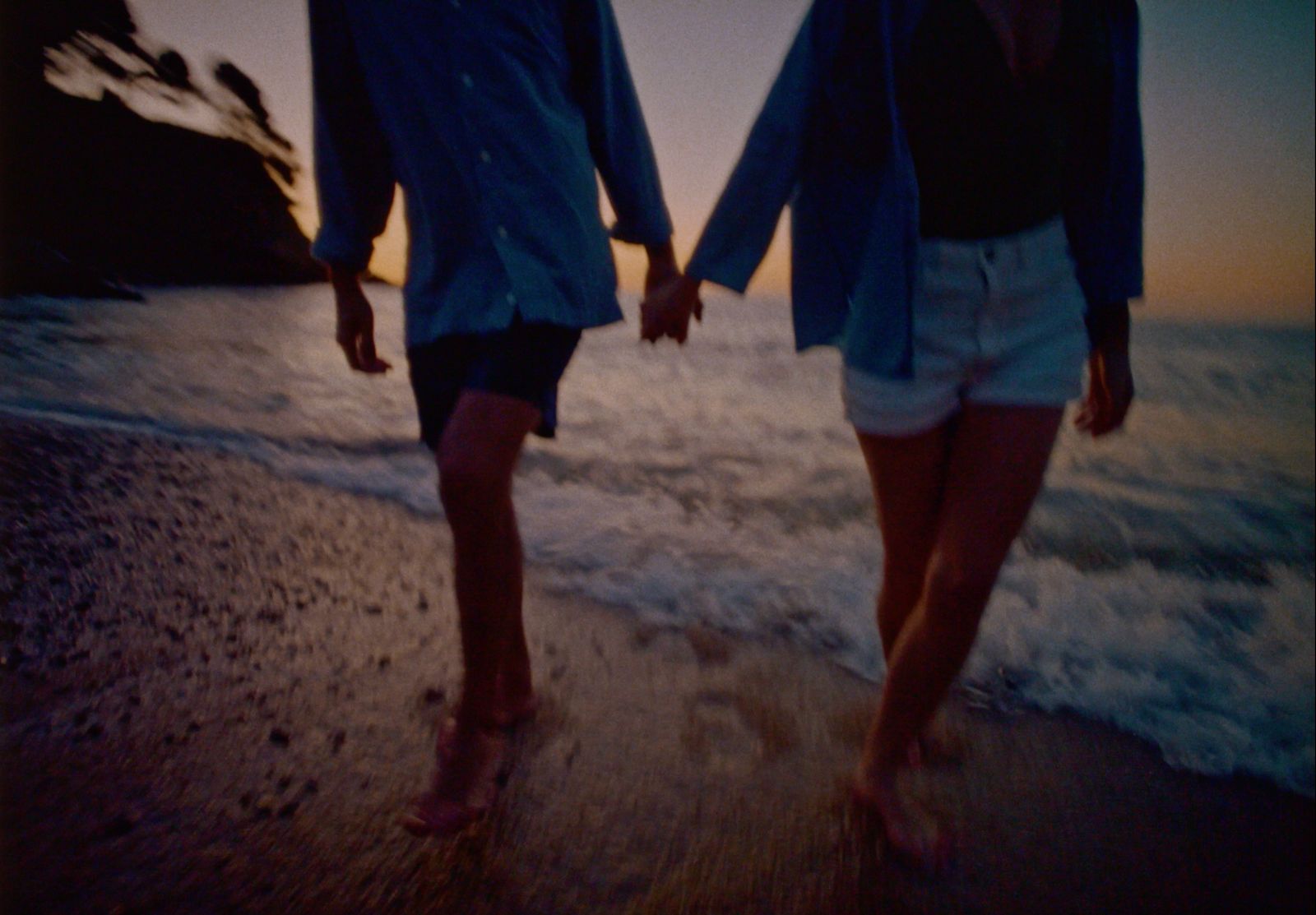 two people walking on the beach holding hands