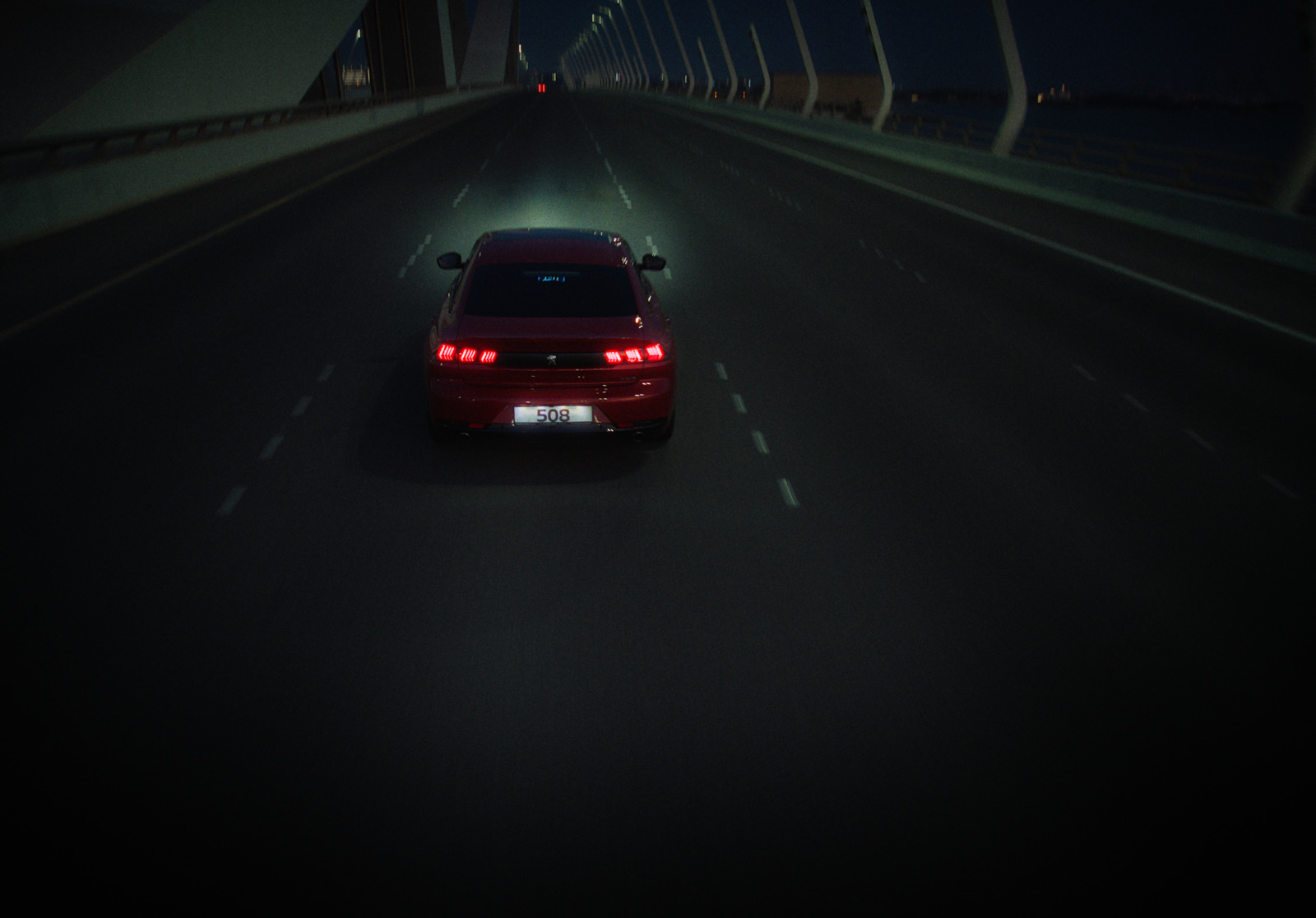 a red car driving down a highway at night