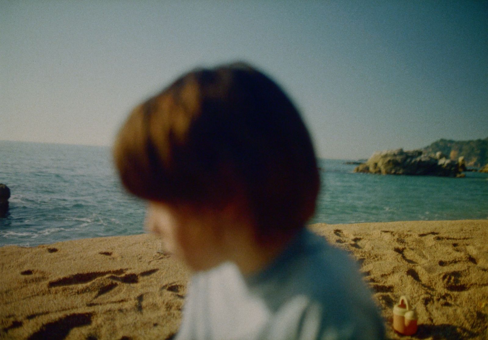 a young boy sitting on top of a sandy beach