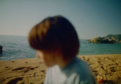 a young boy sitting on top of a sandy beach