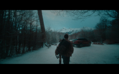 a person walking in the snow with a car in the background