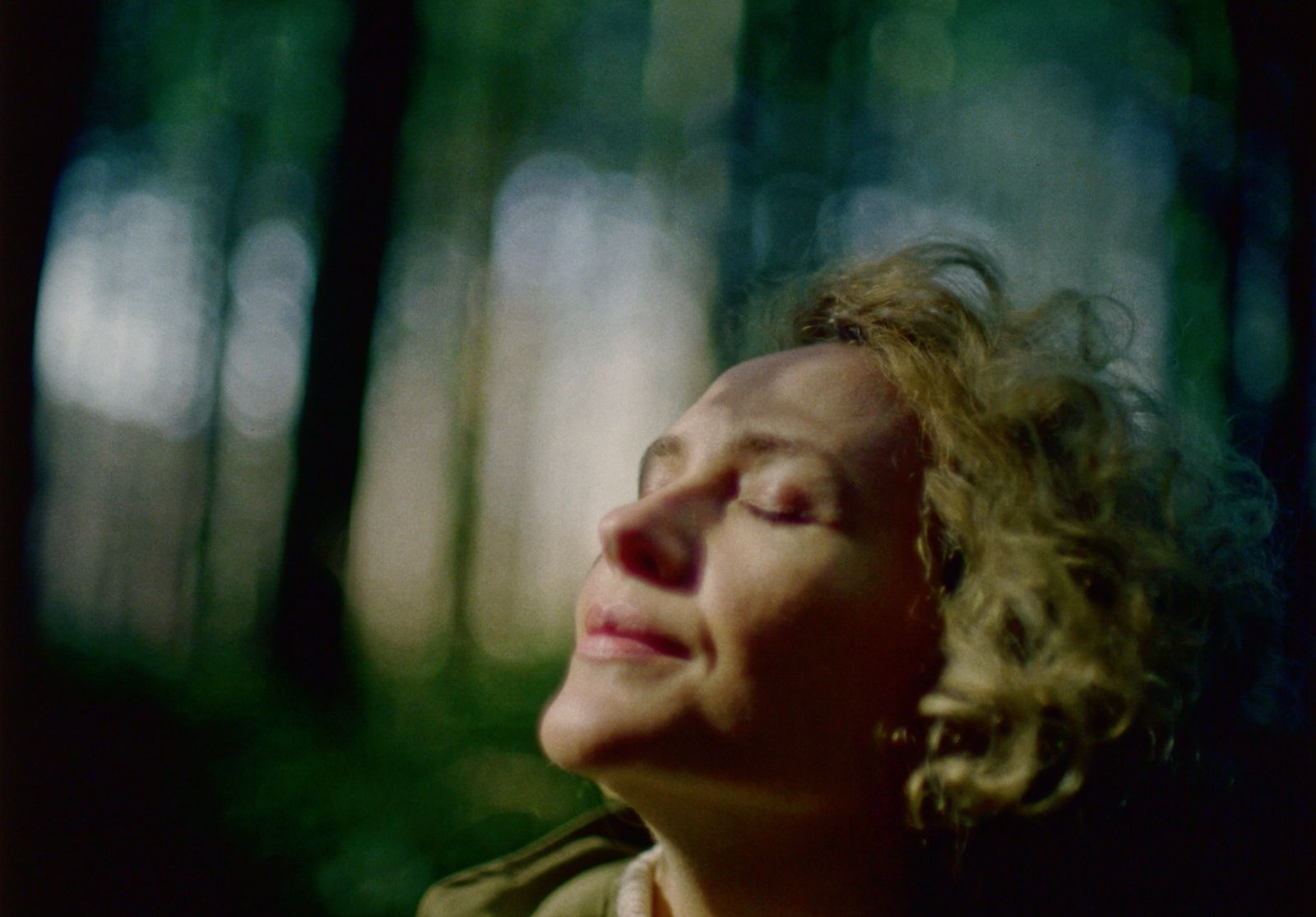 a woman in a forest with her eyes closed