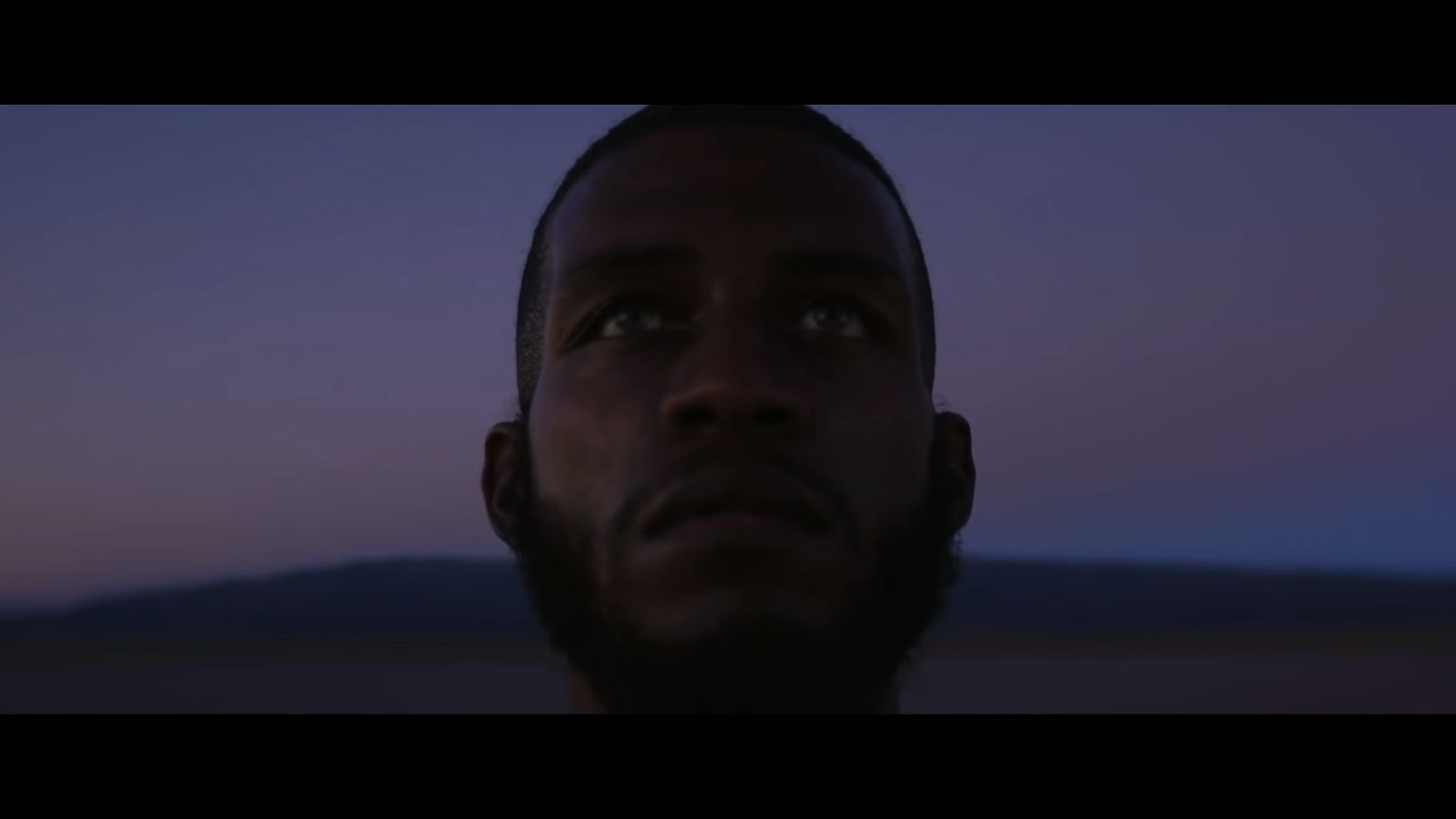 a man looking up at the sky with a mountain in the background