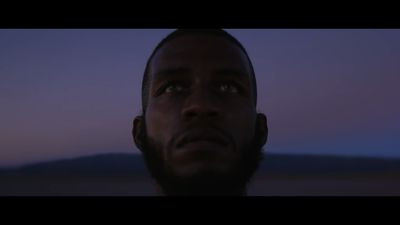 a man looking up at the sky with a mountain in the background